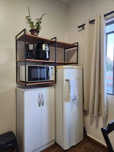 a kitchen with a microwave on top of a refrigerator at Quarto central em ótima localização in Curitiba