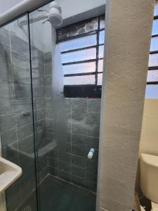 a shower with a glass door in a bathroom at Quarto central em ótima localização in Curitiba