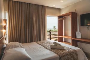 a bedroom with a bed with a window and a television at Casa Mandala - Rooftop com Jacuzzi e Vista Mar in Barra Grande
