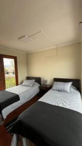 two beds in a room with a window at Global residencial in Rancagua +8 photos