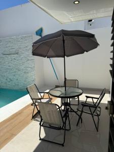 a table with chairs and an umbrella in a room at Casa Brisas del Sur in San Juan del Sur