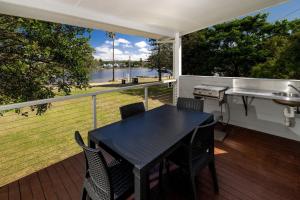 a table and chairs on a deck with a view of the water at Big4 Sydney Lakeside Holiday Park in Narrabeen