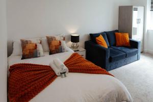 a bedroom with a bed and a blue couch at The Snug by JS Apartments in Blackburn