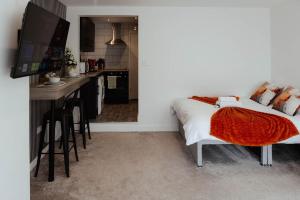 a bedroom with a bed and a kitchen at The Snug by JS Apartments in Blackburn