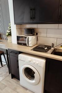 a kitchen with a washing machine and a microwave at The Snug by JS Apartments in Blackburn +9 photos