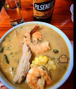 a bowl of soup with shrimp and a bottle of beer at Los Chaskalitos in Malchinguí