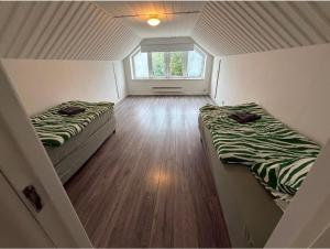 two beds in a small room with a window at Four bedroom house close to the beach in Abbekås