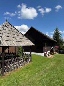 a black barn with a fence in front of it at Babičkina Chalúpka in Pohorelá