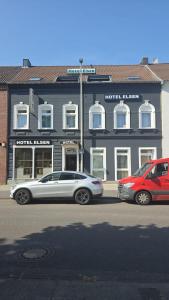 two cars parked on a street in front of a building at Hotel Elsen in Grevenbroich