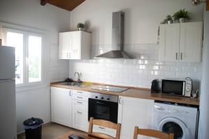 a kitchen with white cabinets and a stove and a microwave at Casa El Palmar - Playa y Jardín in El Palmar