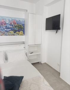 a white bedroom with a bed and a flat screen tv at Room via Florio in Alcamo