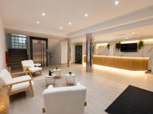 a lobby with white chairs and tables and a television at Hotel Bossh Lido in Benidorm