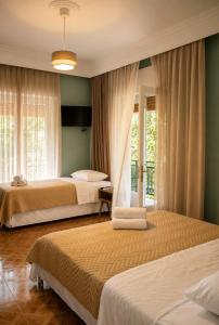 two beds in a bedroom with green walls and windows at Amaya Pine Studio in Panagia