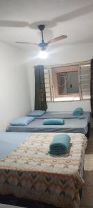 three beds in a room with a ceiling fan at Pousada Alphaville in Aparecida