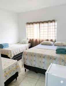 a room with three beds and a window at Pousada Alphaville in Aparecida