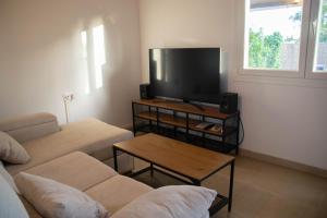 a living room with a couch and a flat screen tv at Casa El Palmar - Playa y Jardín in El Palmar