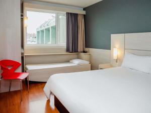 a bedroom with a bed and a window and a red chair at ibis Montevideo Rambla in Montevideo +112 photos