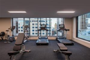 a gym with treadmills and ellipticals in a building at Adina Hobart in Hobart