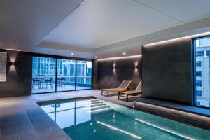 a swimming pool in a hotel room with windows at Adina Hobart in Hobart