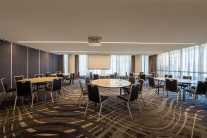 a conference room with tables and chairs and a screen at Adina Hobart in Hobart