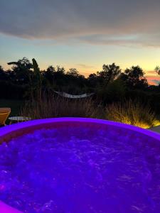 a hot tub filled with purple water at sunset at La Fontana Glamping in Caria