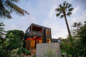 a black house with a palm tree in front of it at The Royale Bundeena in Bundeena