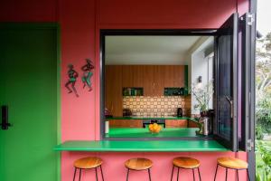 a kitchen with green and red walls and stools at The Royale Bundeena in Bundeena
