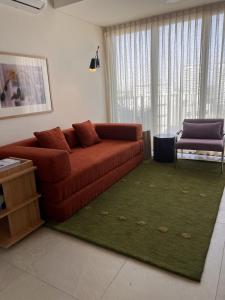 a living room with a brown couch and a green rug at Visa Trip Cozy Stay in Guadalajara