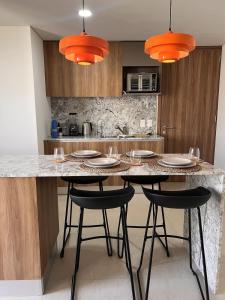 a kitchen with a table with chairs and orange lights at Visa Trip Cozy Stay in Guadalajara