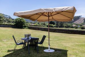a table and chairs under an umbrella in a field at Casa Raxón Ferrol in Ferrol