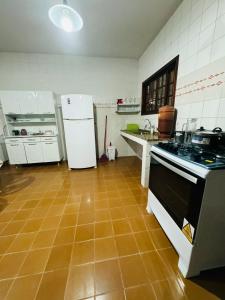 a kitchen with white appliances and a tile floor at Casa do Carol Sana in Macaé