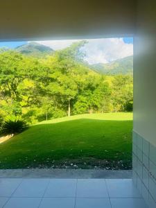 a view of a green field with mountains in the background at Casa do Carol Sana in Macaé