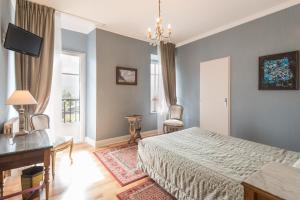 a bedroom with a bed and a desk and a window at Logis Hôtel Beau Site in Argelès-Gazost