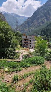 Ein Gebäude auf einem Feld mit Bergen im Hintergrund in der Unterkunft Parvati's Edge in Kasol