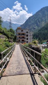 Eine Brücke über eine Straße mit einem Gebäude im Hintergrund in der Unterkunft Parvati's Edge in Kasol
