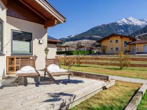 two chairs on a wooden deck with mountains in the background at Bruggerheim in Niedernsill