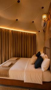a bedroom with a bed with white sheets and pillows at WADI RUM REGENCY BUBBLE lUXURY in Wadi Rum