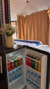 an open refrigerator filled with drinks and a vase at WADI RUM REGENCY BUBBLE lUXURY in Wadi Rum