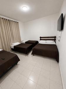 a room with three beds and a flat screen tv at Hotel Classic in Porangatu