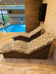 a swimming pool with two cushioned chairs in front of a pool at Emperus Spa in Veliko Gradište