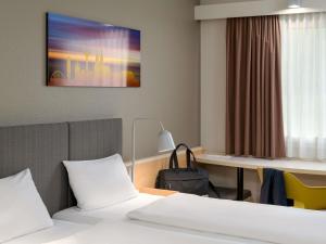 a room with a bed and a desk and a table at ibis Hotel Köln Airport in Cologne