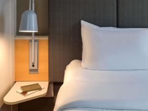 a bed with a white pillow and a table with a lamp at ibis Hotel Köln Airport in Cologne