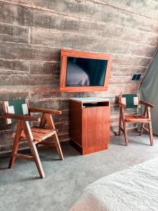 a room with two chairs and a tv on a wall at Danselis Boutique Hotels in Telchac Puerto