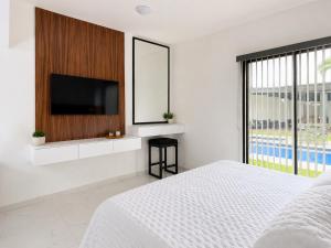a white bedroom with a tv and a bed at Lucmar Jardín boutique in Cuernavaca