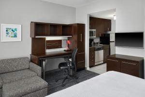 a room with a desk and a couch and a kitchen at TownePlace Suites by Marriott Springfield in Springfield