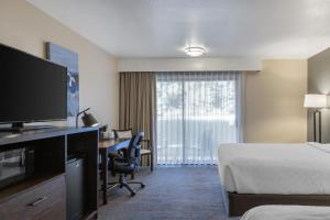 a hotel room with a bed and a desk with a television at Best Western Sunridge Inn & Conference Center in Baker City