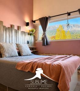 a bedroom with a large bed with a large window at Cabañas Sublime Bolson in El Bolsón