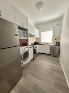 a kitchen with a refrigerator and a washer and dryer at Esplanade Bliss in Cronulla