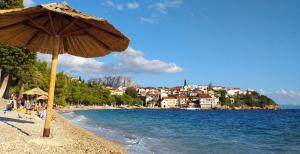 a beach with an umbrella and the water and buildings at Apartments and rooms by the sea Podaca, Makarska - 16160 in Podaca