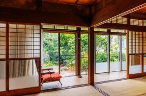 an open room with glass doors and a chair at 古民家おにぎり in Otsu